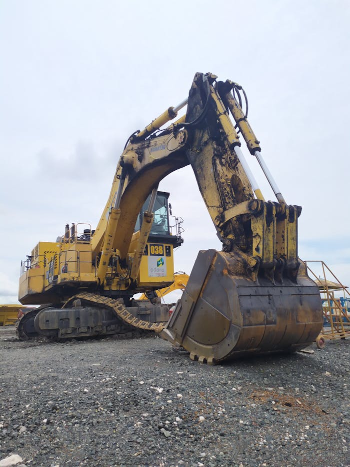 Large yellow excavator at a construction site in Indonesia under a cloudy sky.